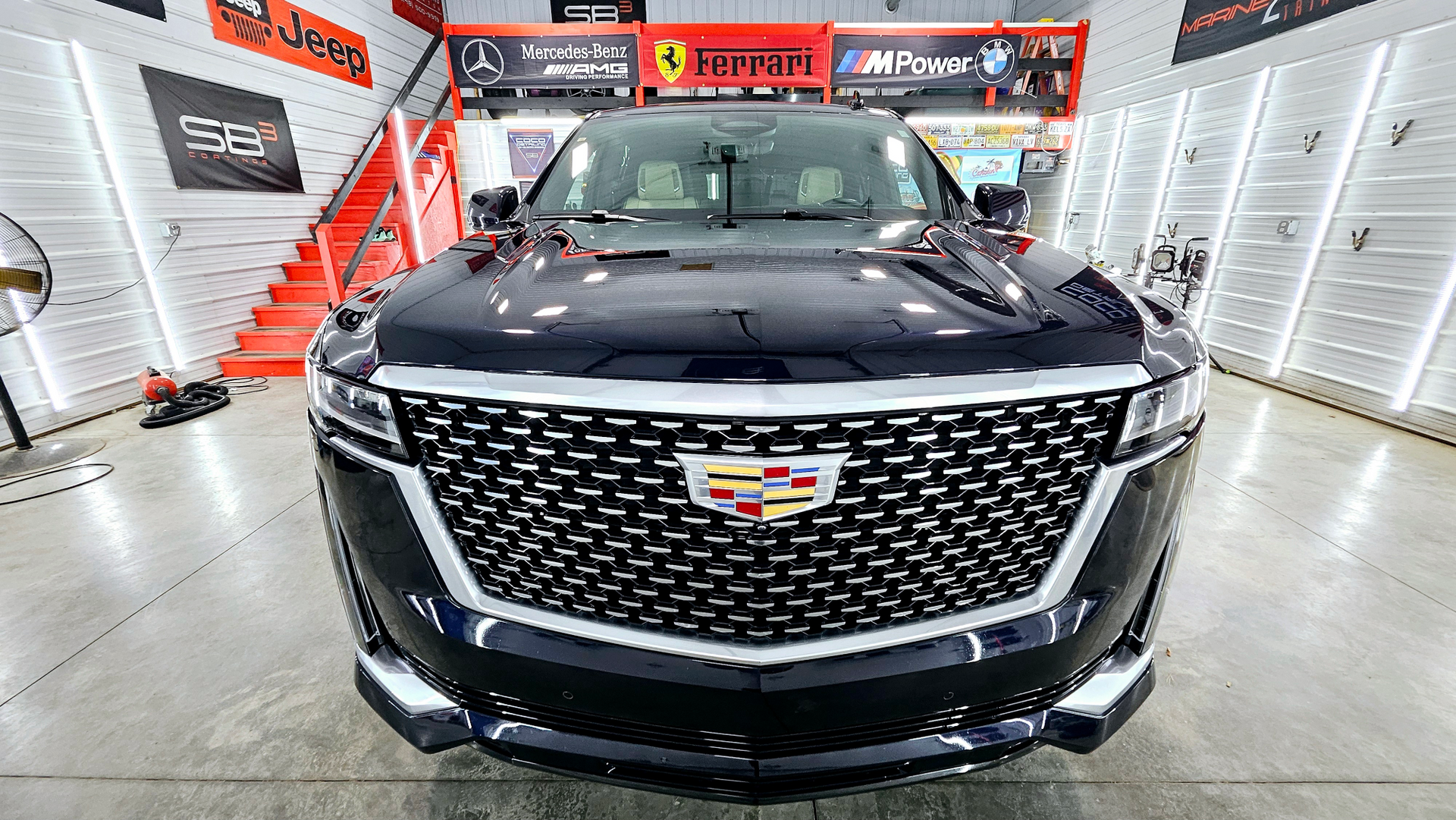 A black cadillac escalade is parked in a garage.
