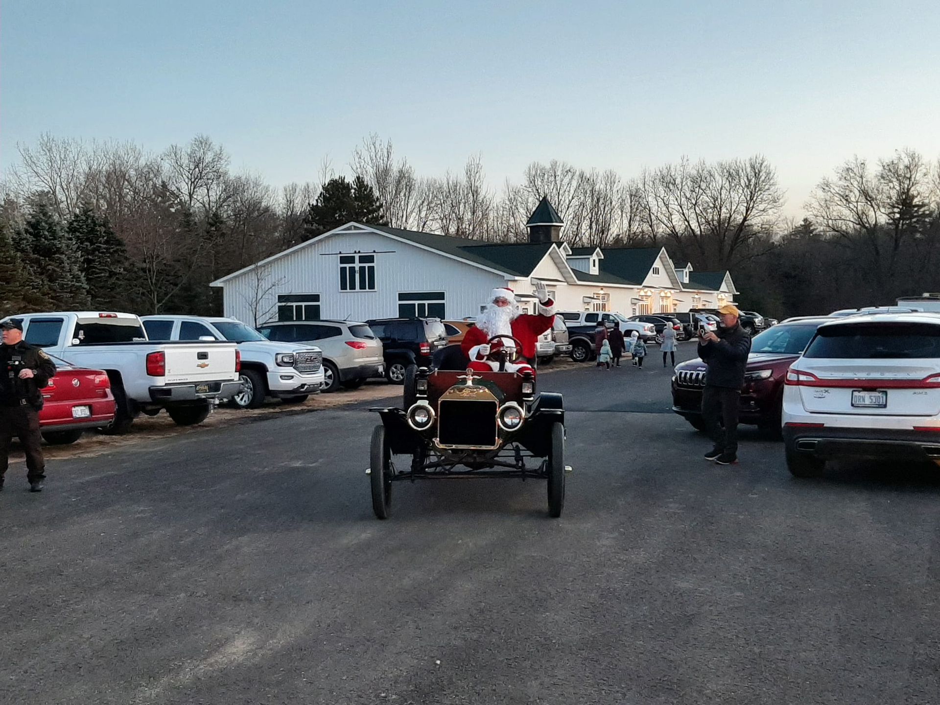 Vintage red car parade in a parking lot beside a white building at dusk