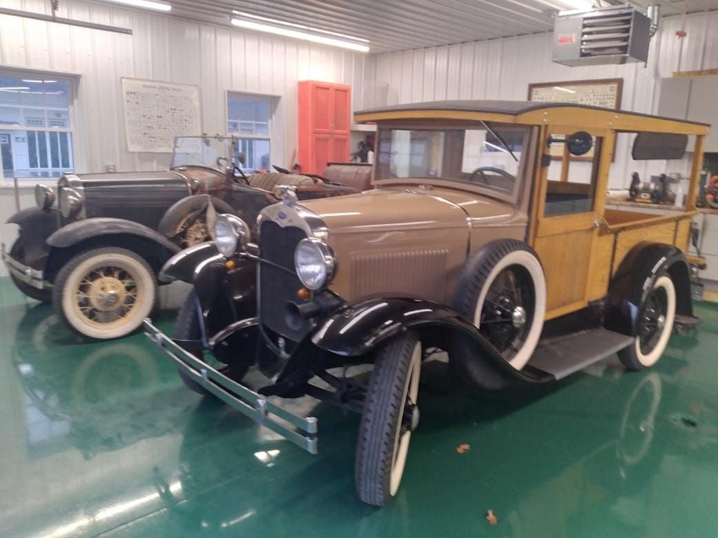 Vintage brown-and-black classic car in a museum showroom with a green floor