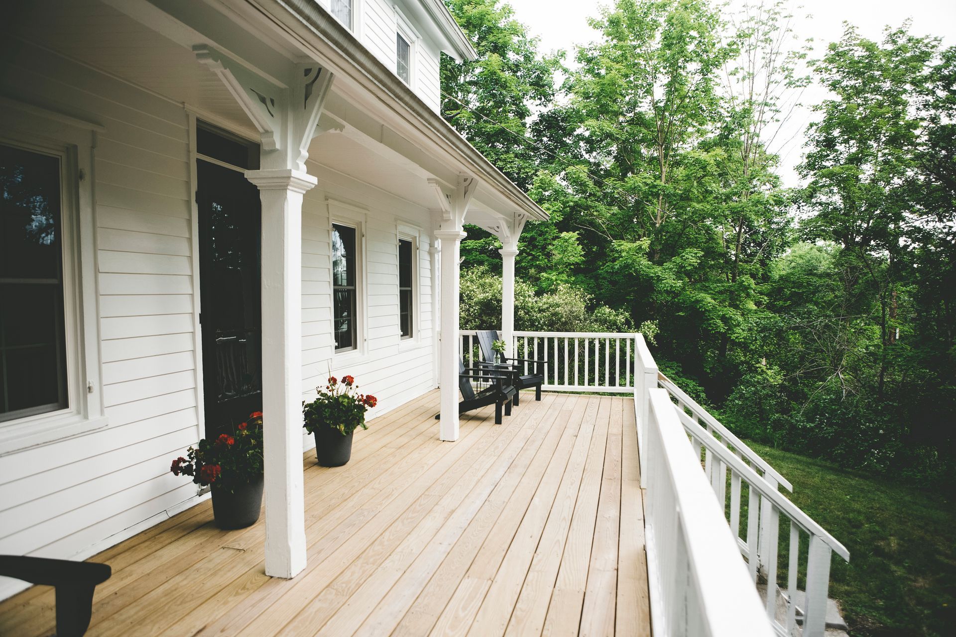 A white house with a large porch surrounded by trees A white house with a large porch surrounded by trees