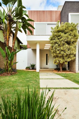 A modern house with a lush green lawn and trees in front of it. A modern house with a lush green lawn and trees in front of it.