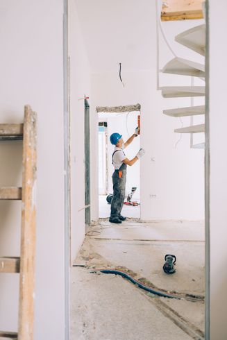 A man is working on a door in a room under construction. A man is working on a door in a room under construction.