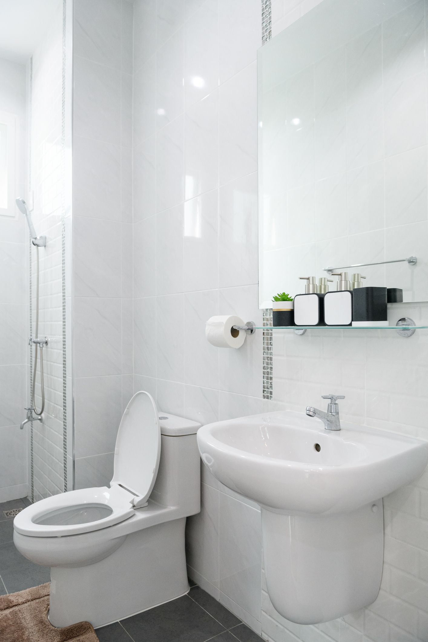 A bathroom with a toilet , sink and shower.
