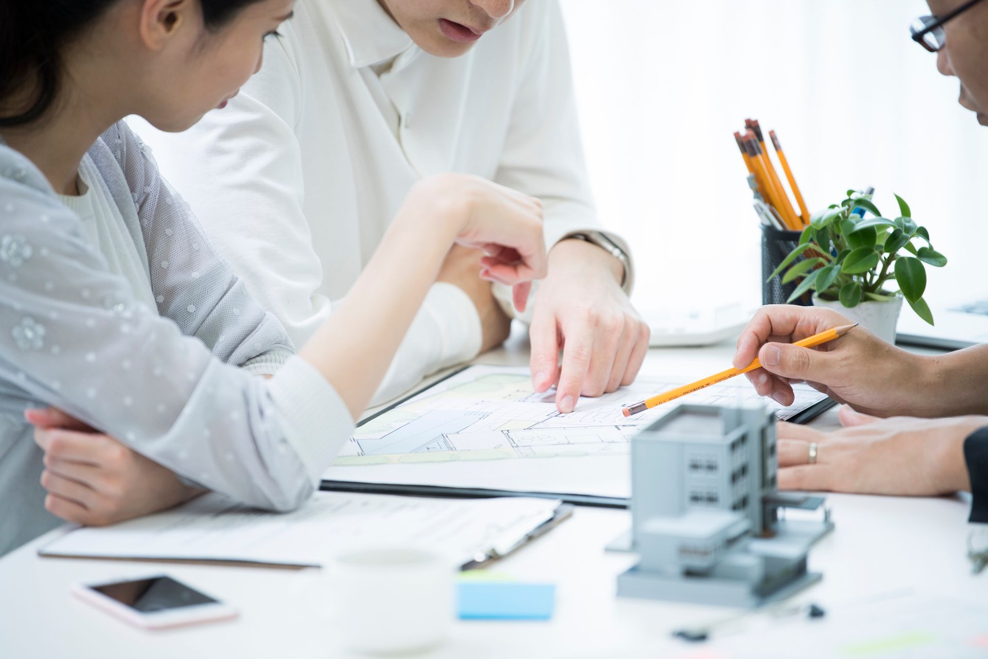 A group of people are sitting around a table looking at a blueprint. A group of people are sitting around a table looking at a blueprint.