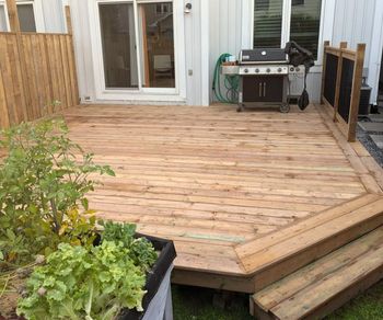 A wooden deck with a grill and a planter of lettuce. A wooden deck with a grill and a planter of lettuce.