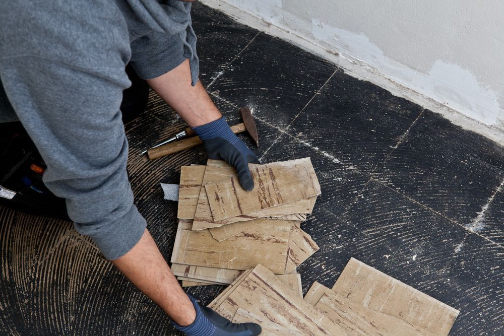 Person Kneeling, Removing Sections of Flooring with Gloves — C & S Building In Bentley, NSW