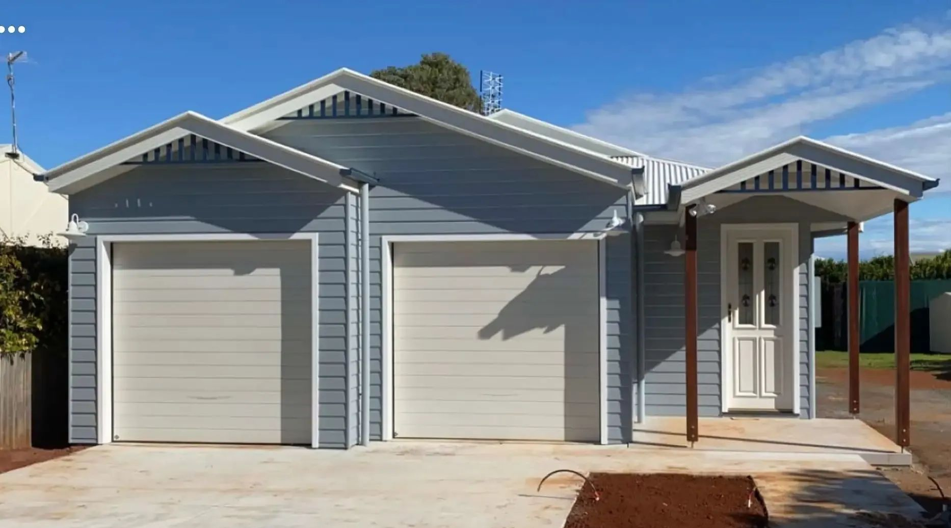Blue-sided building with two garage doors and a front door under a small porch — C & S Building In Bentley, NSW