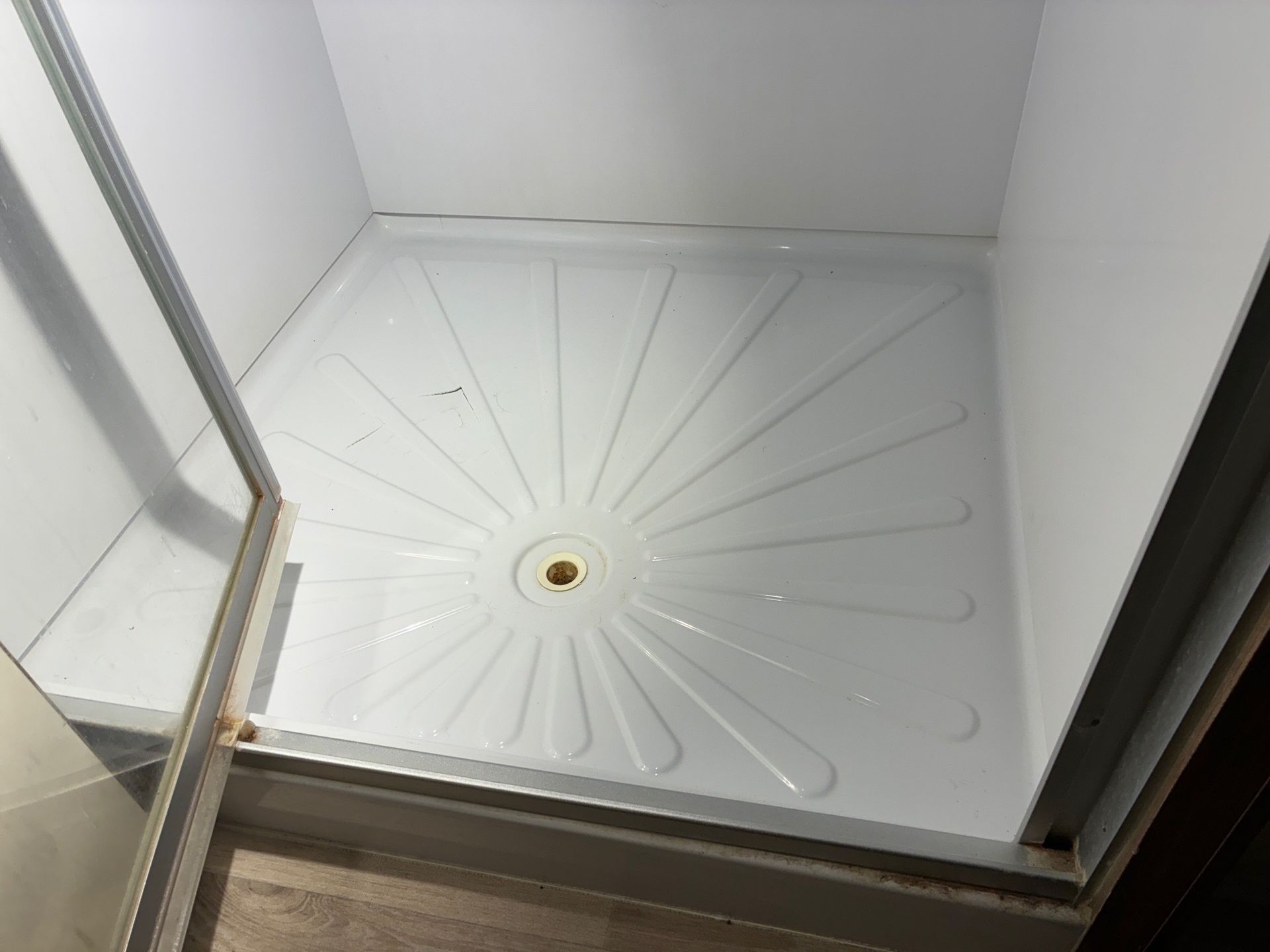 Red Fox installing a White shower stall with a center drain and glass door.