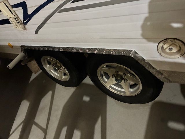 Two trailer wheels with silver rims and a diamond plate fender.