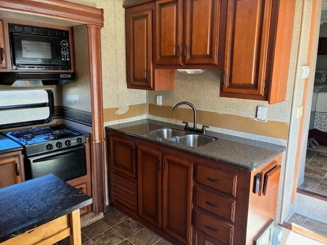 Red Fox before installing anRV kitchen with brown cabinets, stainless steel sink, stove, and microwave.