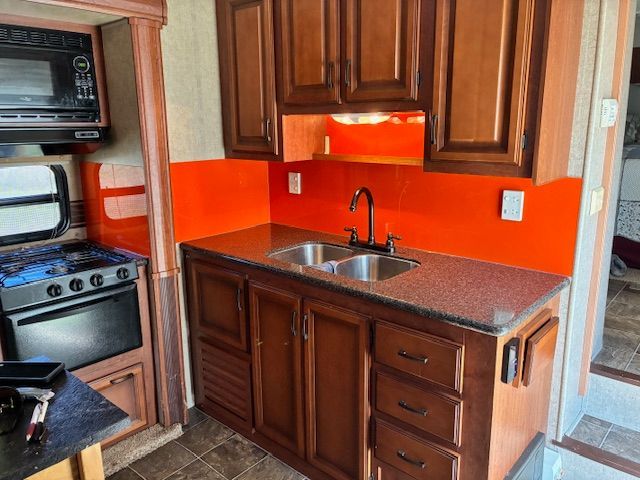 Red Fox installing aRV kitchen with brown cabinets, orange backsplash, and a double sink.