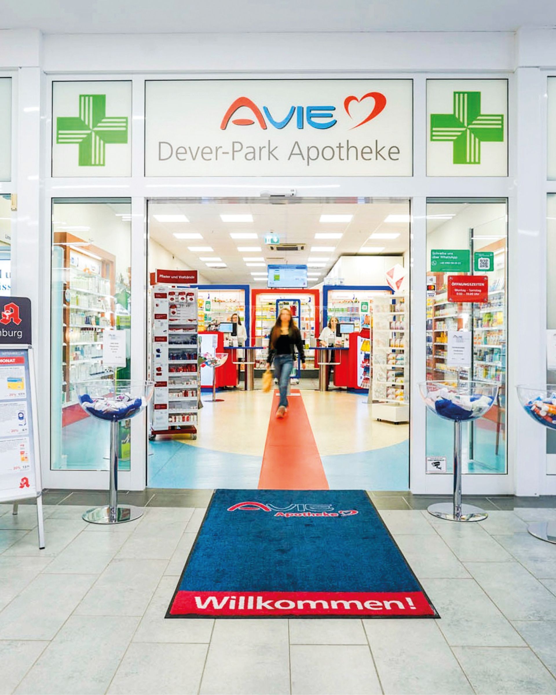 Eine Frau geht durch die Tür einer Ave Dever Park Apotheke