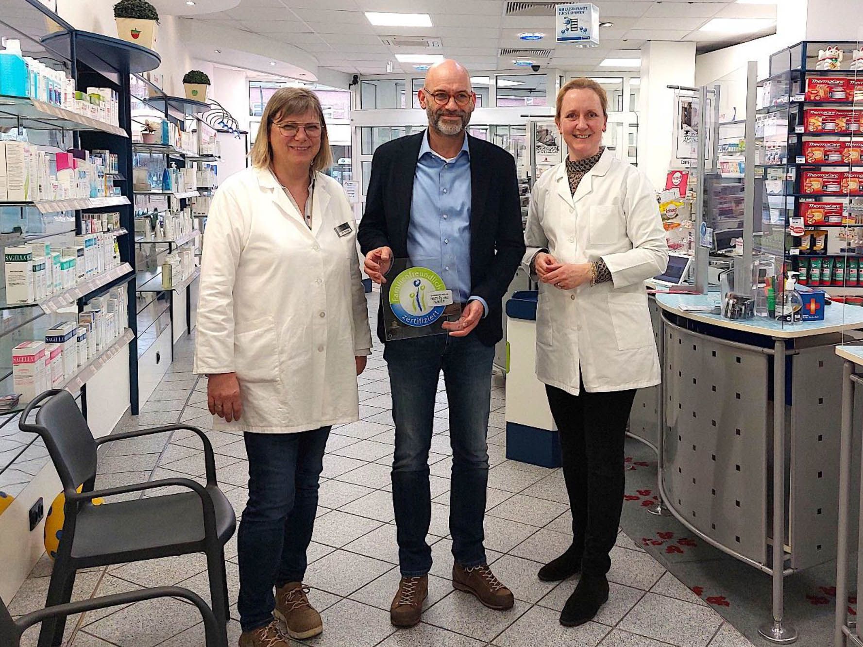 Ein Mann und zwei Frauen stehen in einer Apotheke.
