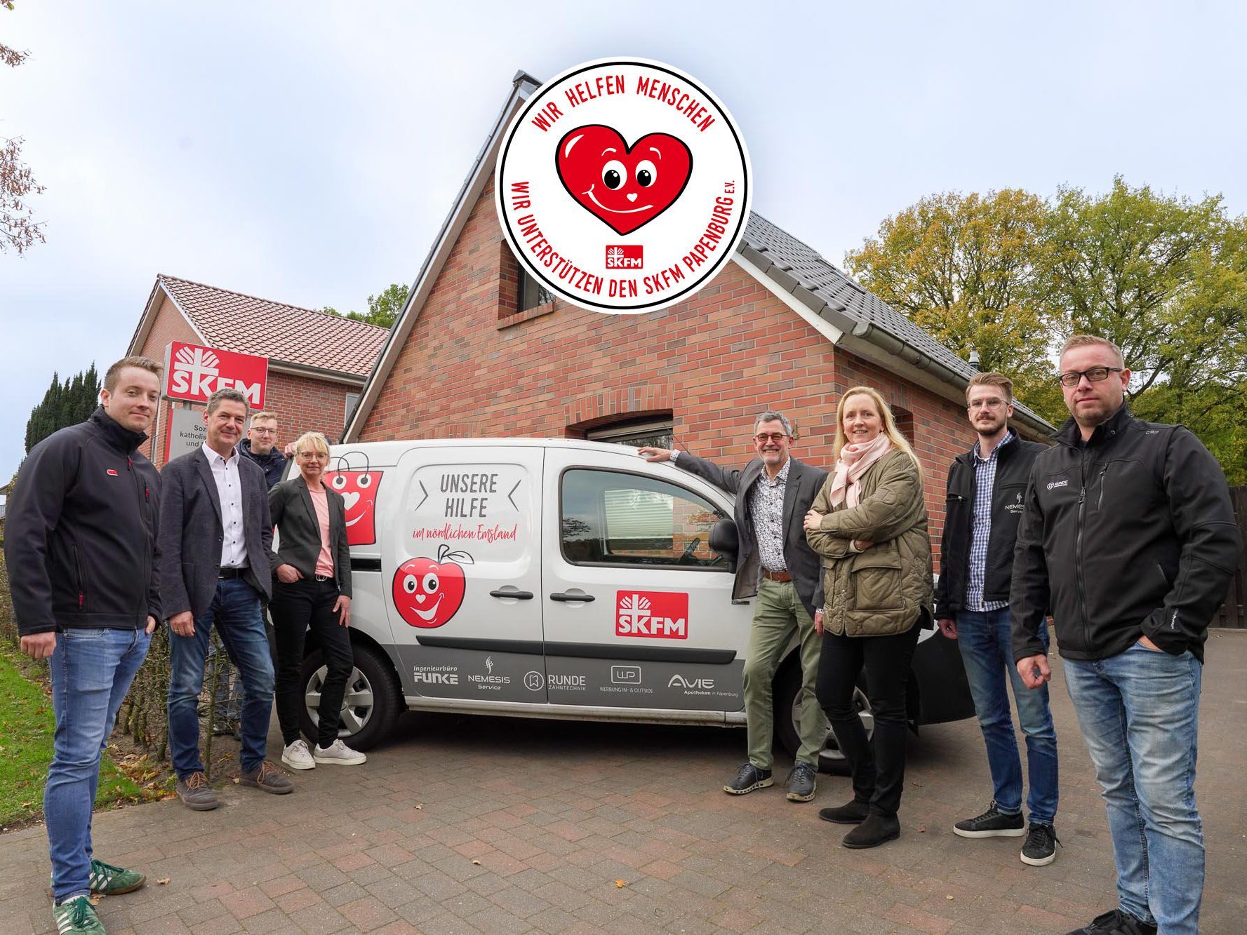 Eine Gruppe von Menschen steht vor einem Lieferwagen des SKFM Papenburg.