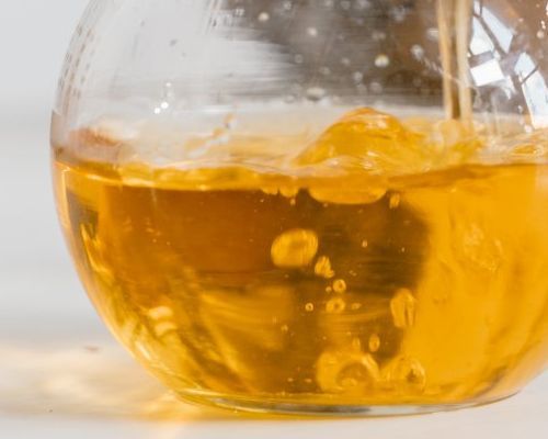 A close up of a glass container filled with yellow liquid.