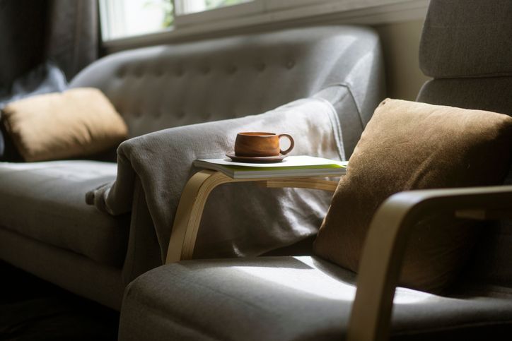 Una sedia con una tazza di caffè su un tavolo accanto a un divano.