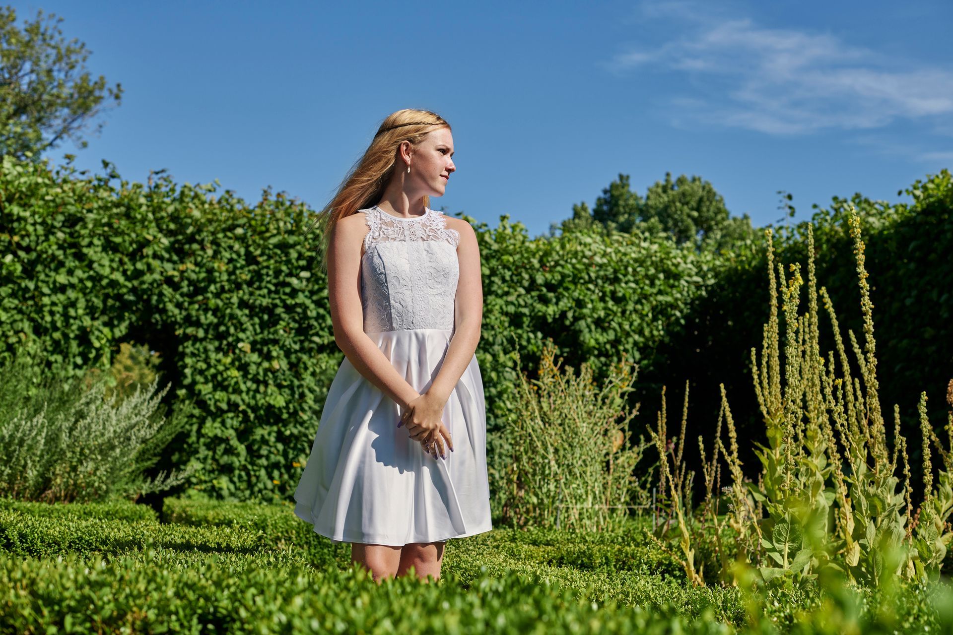 Una donna vestita di bianco è in piedi in un giardino.
