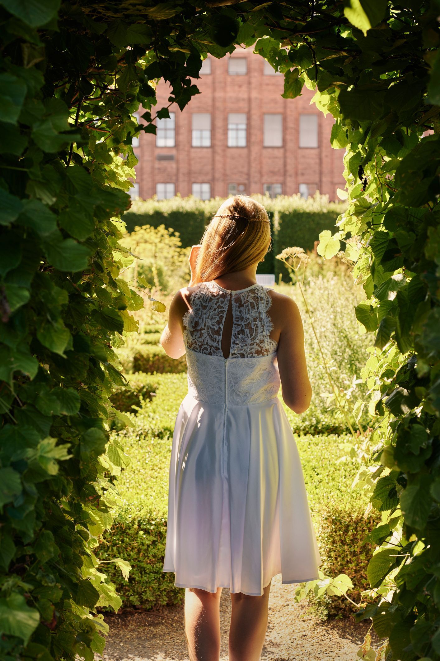 Una donna vestita di bianco è in piedi in un giardino.