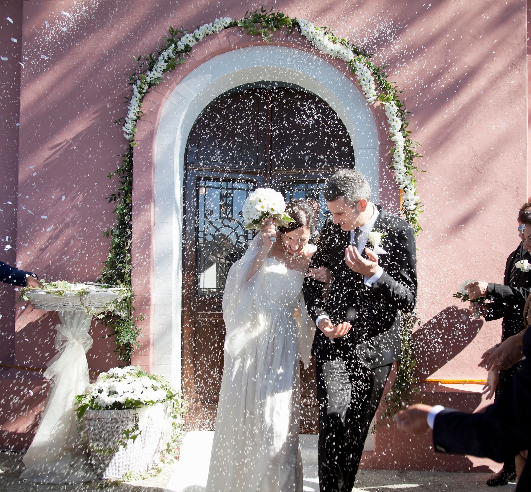Una sposa e uno sposo vengono ricoperti di riso bianco
