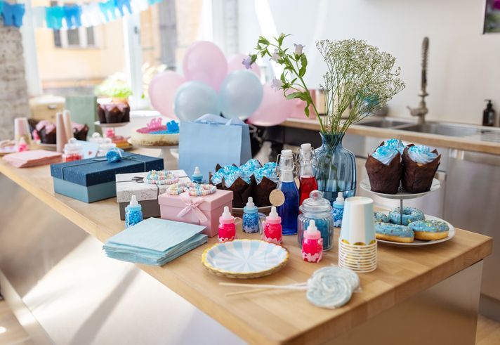 Un tavolo pieno di cupcake, palloncini, regali e altri articoli per un baby shower.