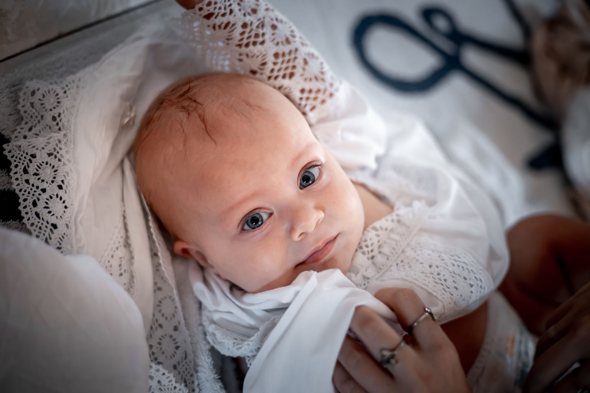 Una donna tiene in braccio un bambino avvolto in una coperta bianca.