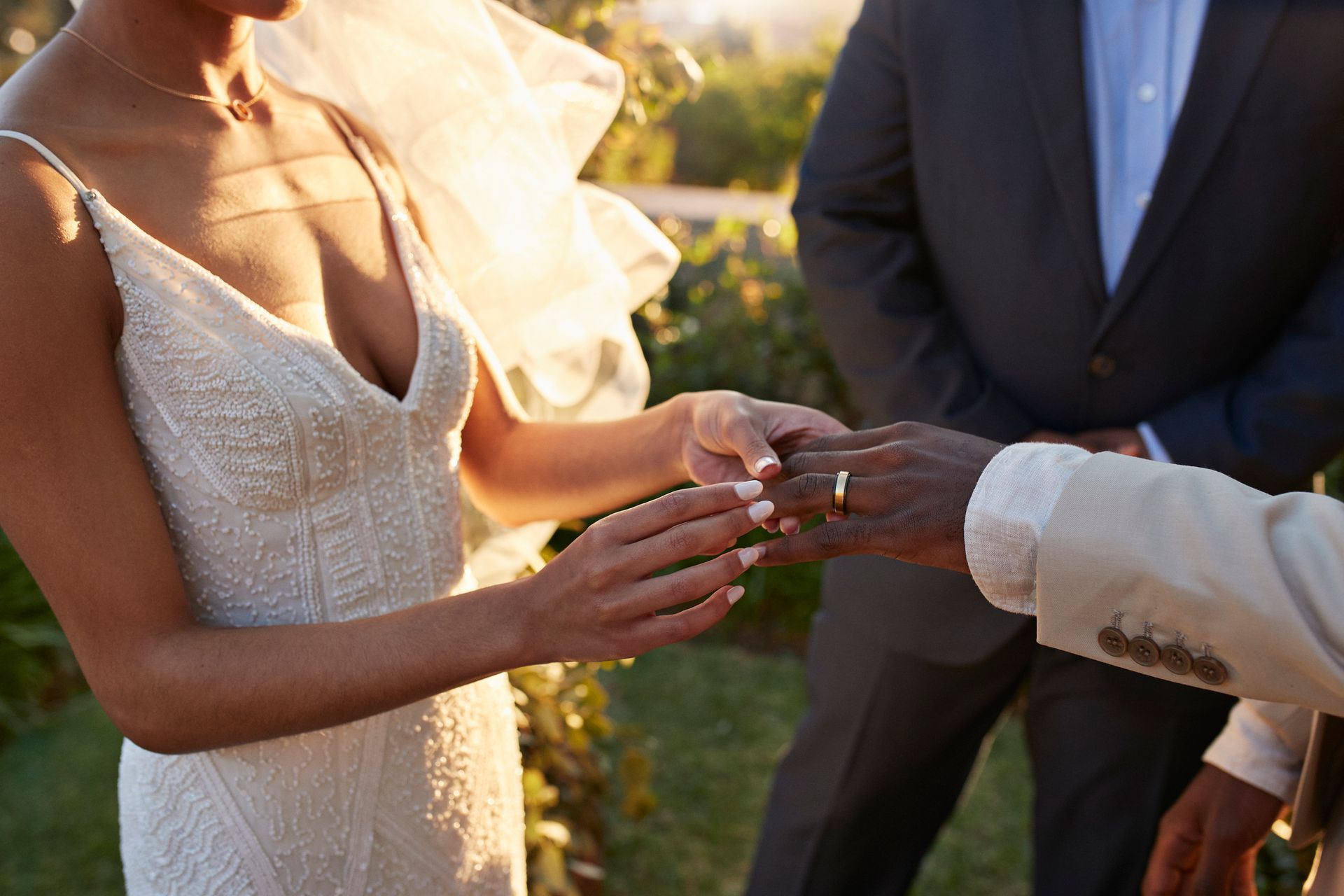Una sposa sta mettendo la fede nuziale al dito dello sposo.