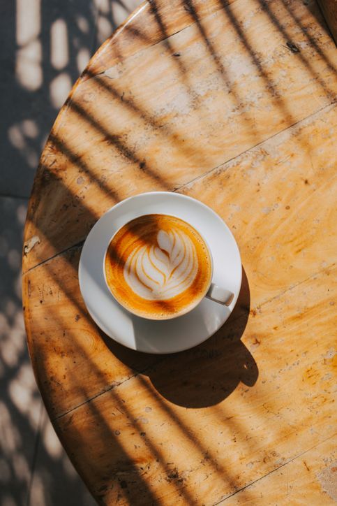 Una tazza di cappuccino su un piattino su un tavolo di legno.