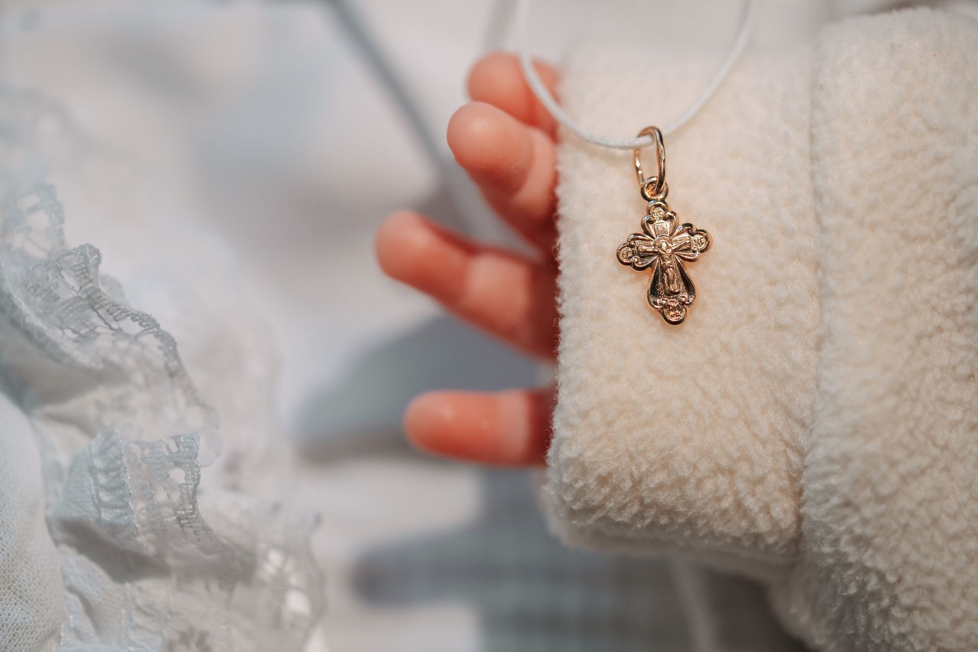 Un bambino tiene in mano un ciondolo a forma di croce appeso a una collana.