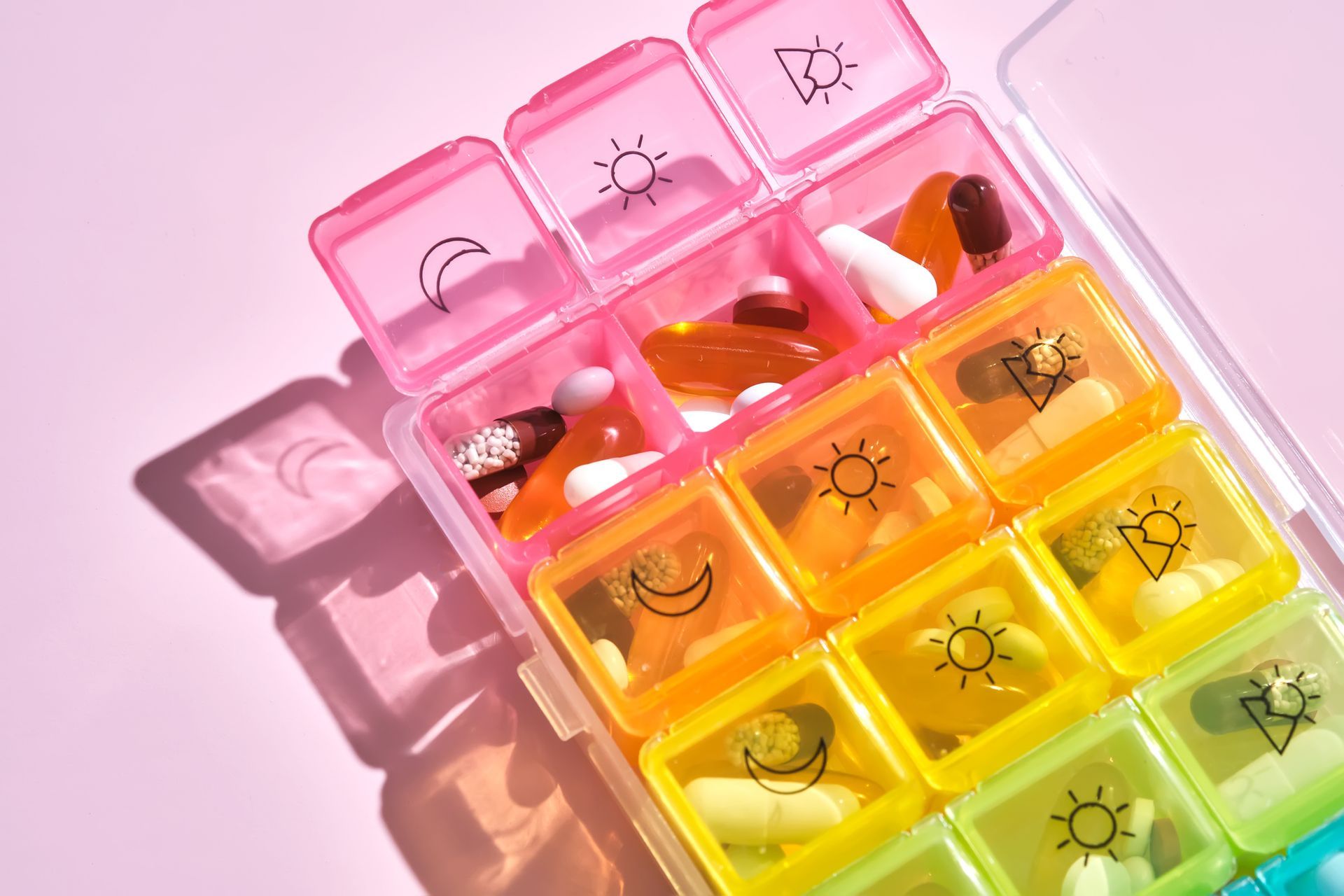 A rainbow colored pill holder with pills in it