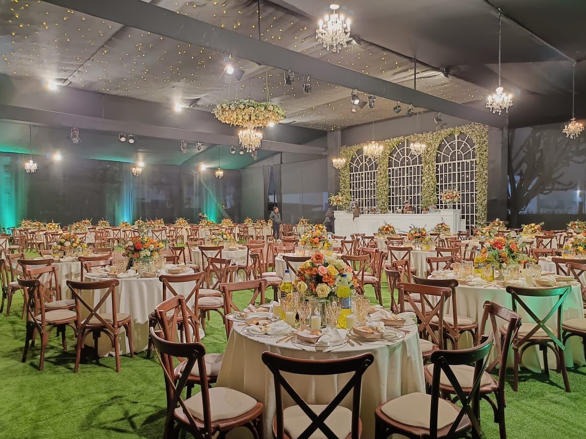 Elegante salón de banquetes con numerosas mesas redondas y centros de mesa florales bajo candelabros