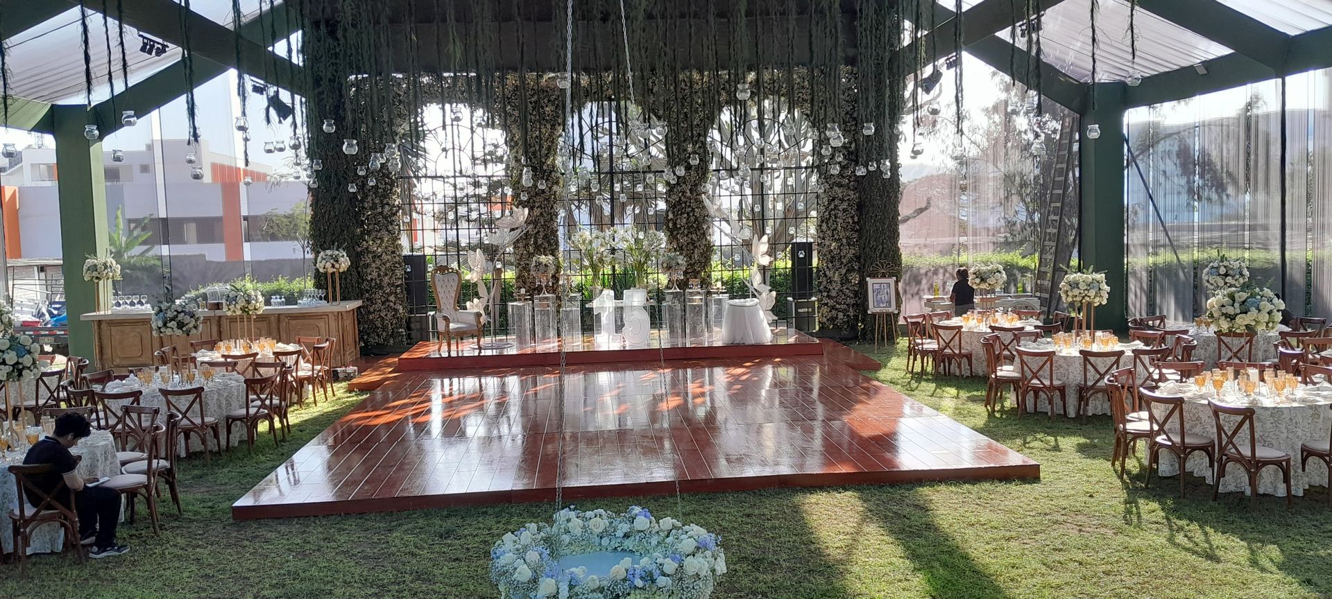 Outdoor dining area with a reflective red pool, hanging greenery, and tables under a shaded canopy