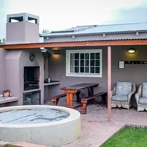 Backyard patio with hot tub, grill, picnic table, and covered seating area