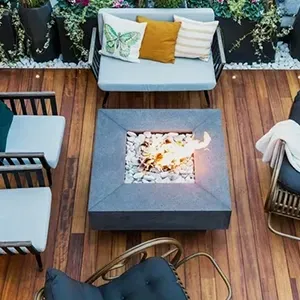 Outdoor patio with wooden deck, square fire pit, and cushioned seating around it.