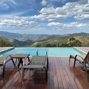 Infinity pool deck overlooking mountains and clouds, with lounge chairs and a table in the foreground