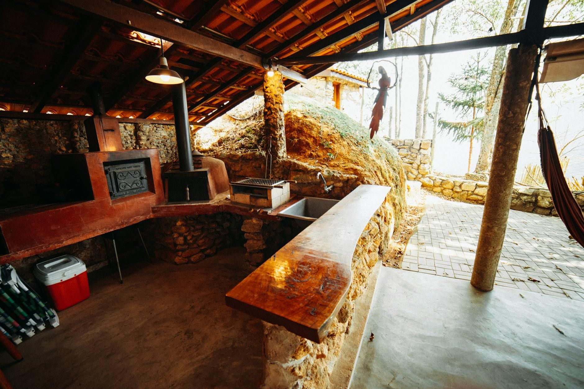 Rustic wooden cabin interior with benches, stone fireplace, and bright sunlight on a snowy outdoor view