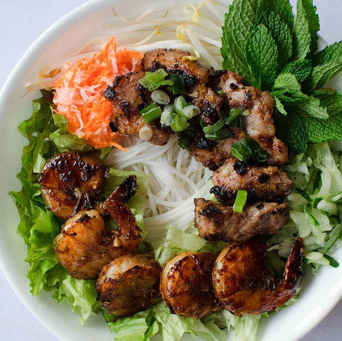 A white plate topped with noodles meat and vegetables