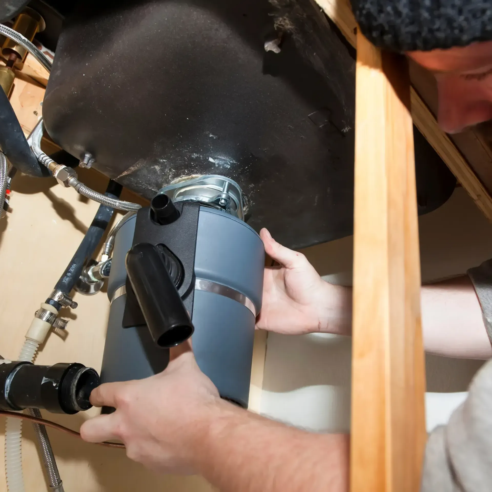 B&B Plumbing - A man is working on a sink with a hose attached to it