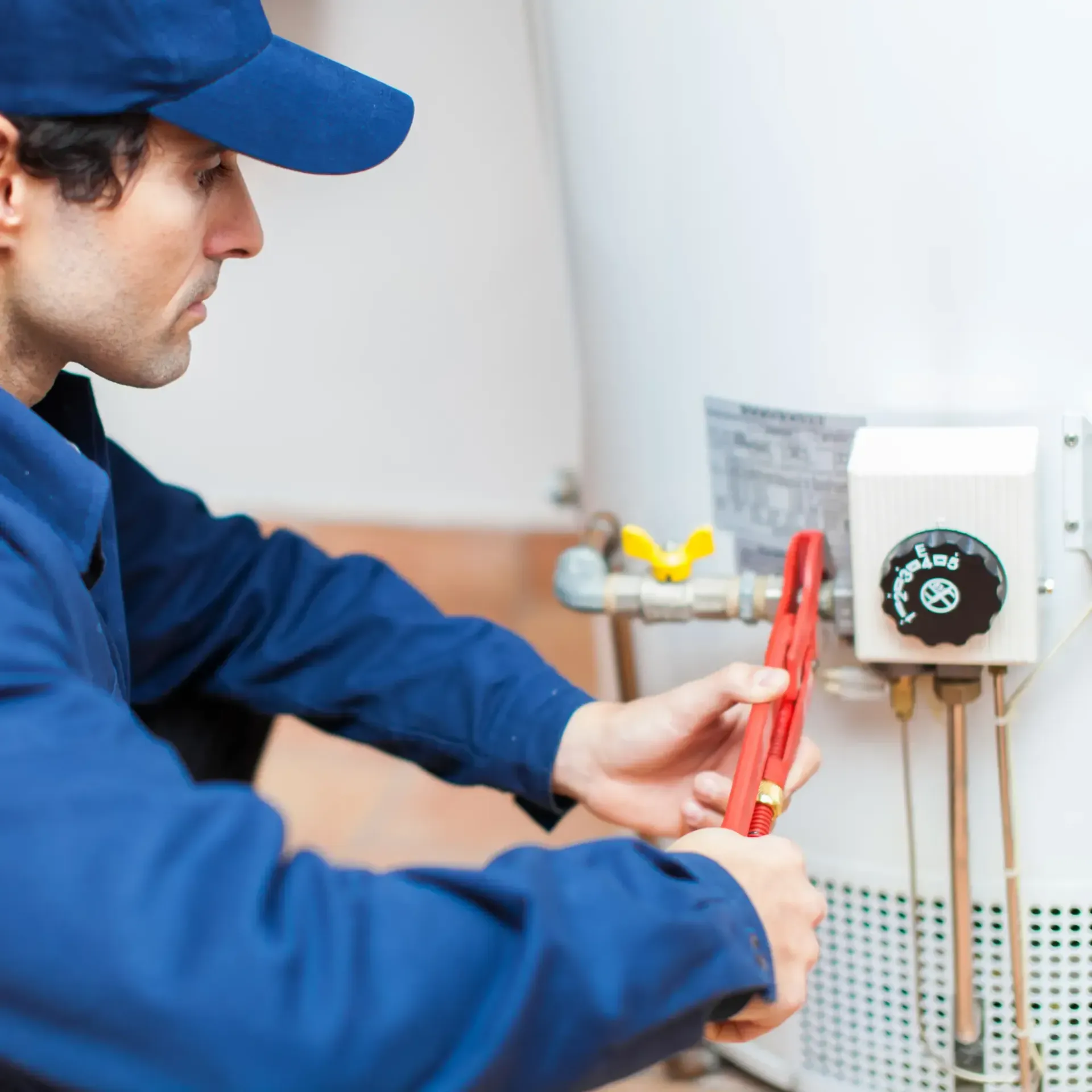 B&B Plumbing Services- A man is fixing a water heater with a wrench