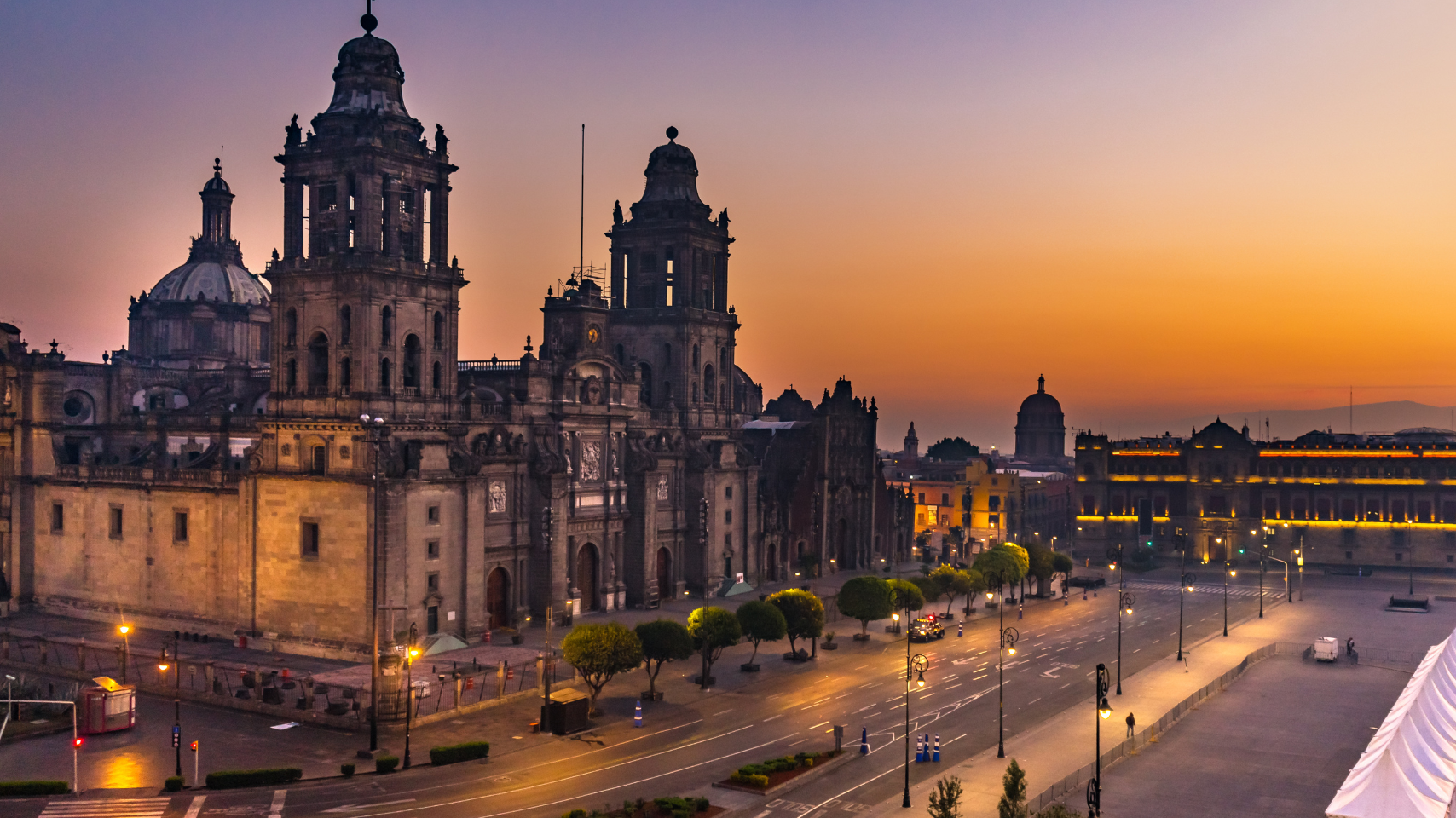 An aerial view of a city at sunset with a large building in the foreground.