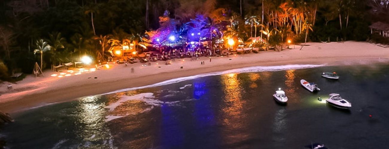 An aerial view of a beach at night with boats in the water.