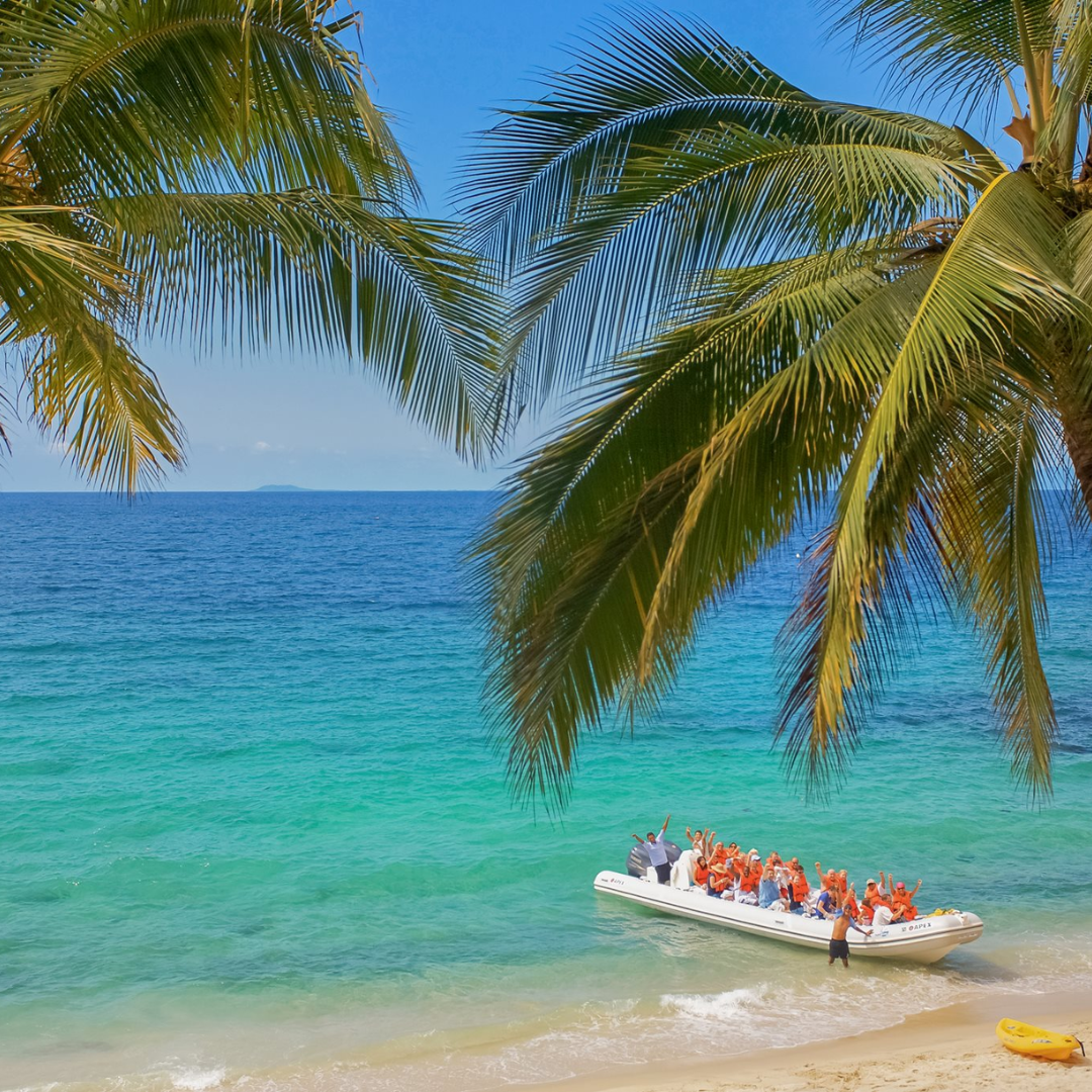 A group of people are in a boat on a tropical beach.