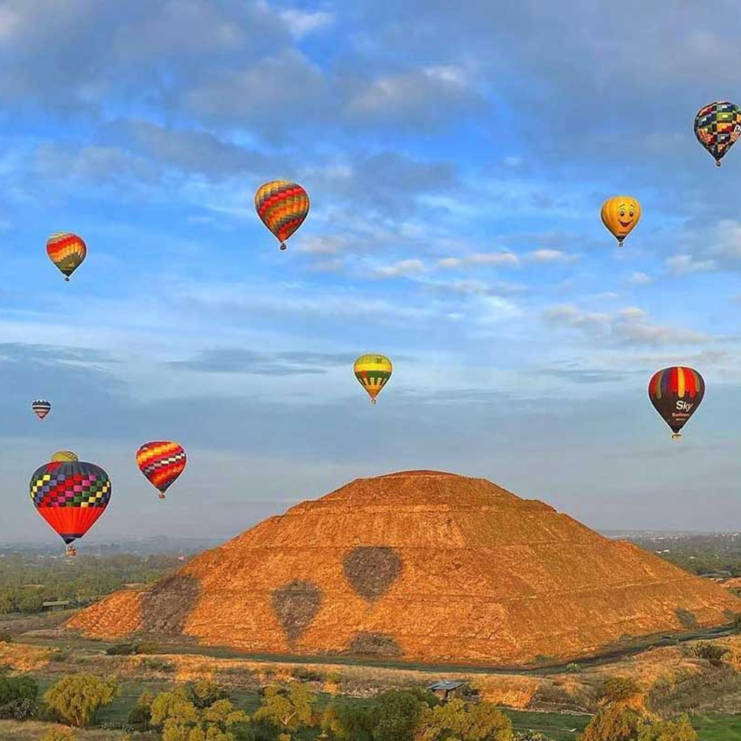 A bunch of hot air balloons are flying over a hill.