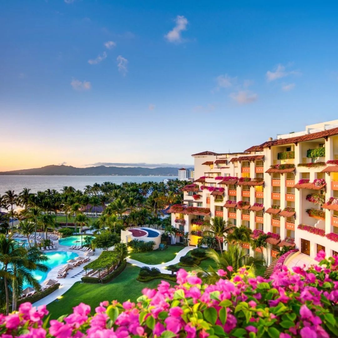A large hotel with a pool and flowers in front of it