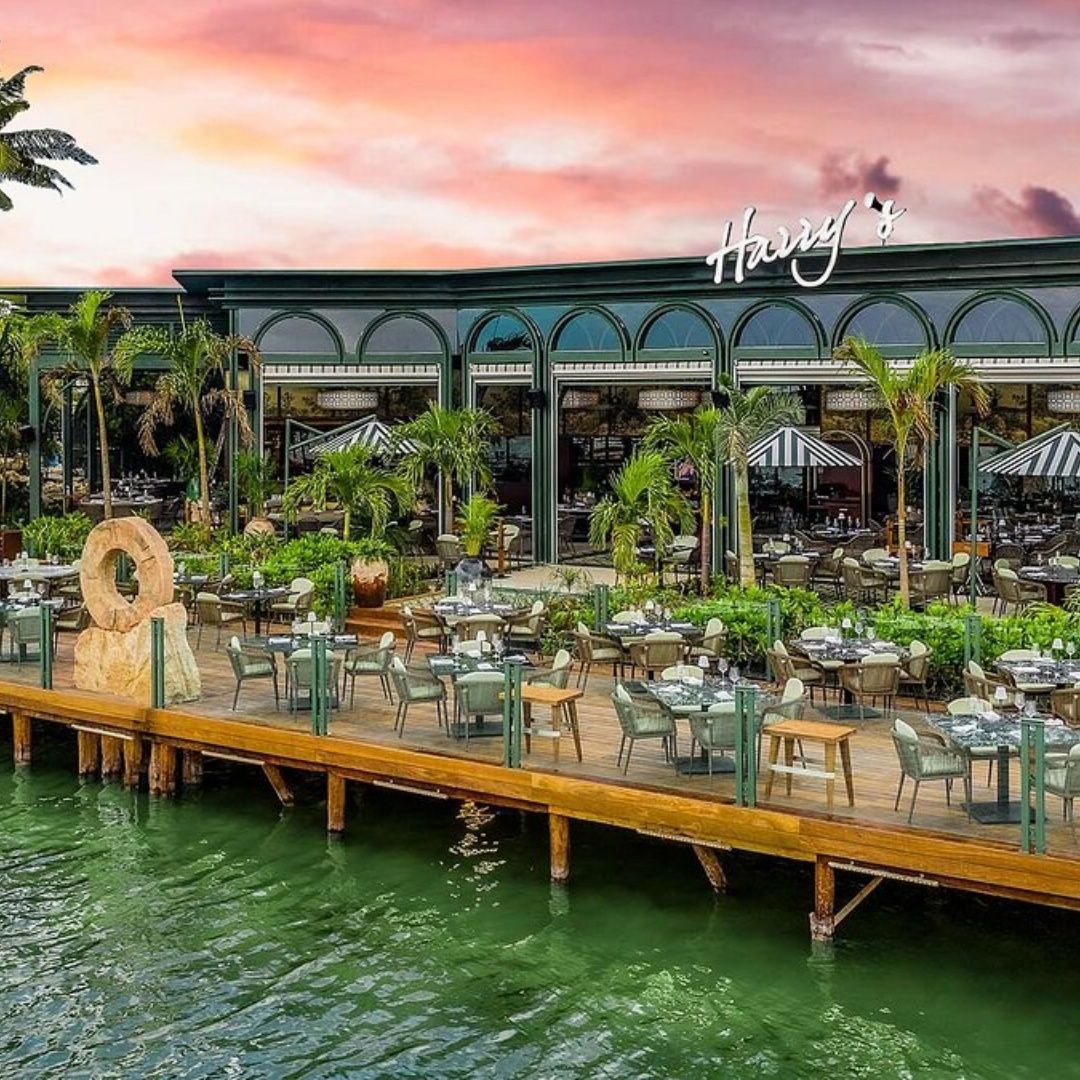 A restaurant with tables and chairs on a dock overlooking the water.