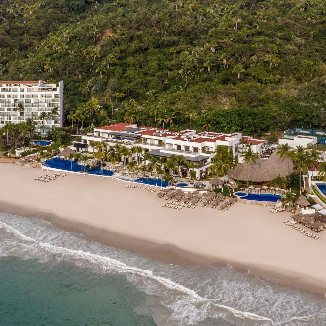 An aerial view of a beach with a hotel in the background