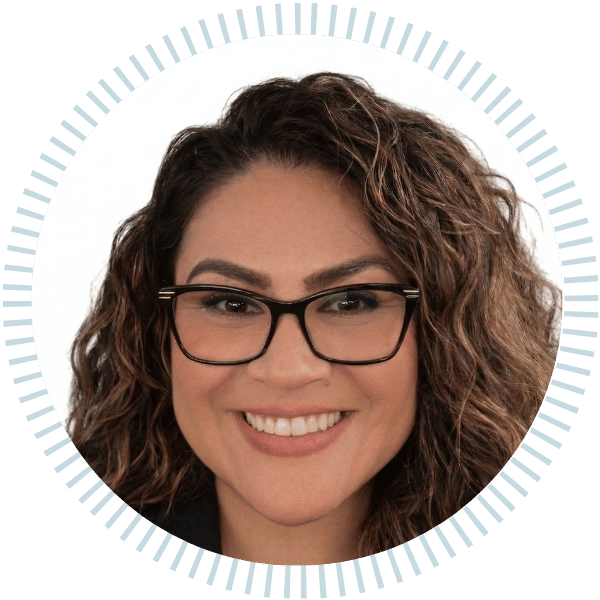 Smiling woman with curly hair and black glasses in a circular profile photo on a light background