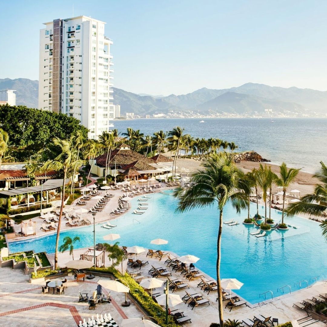 An aerial view of a large swimming pool surrounded by palm trees