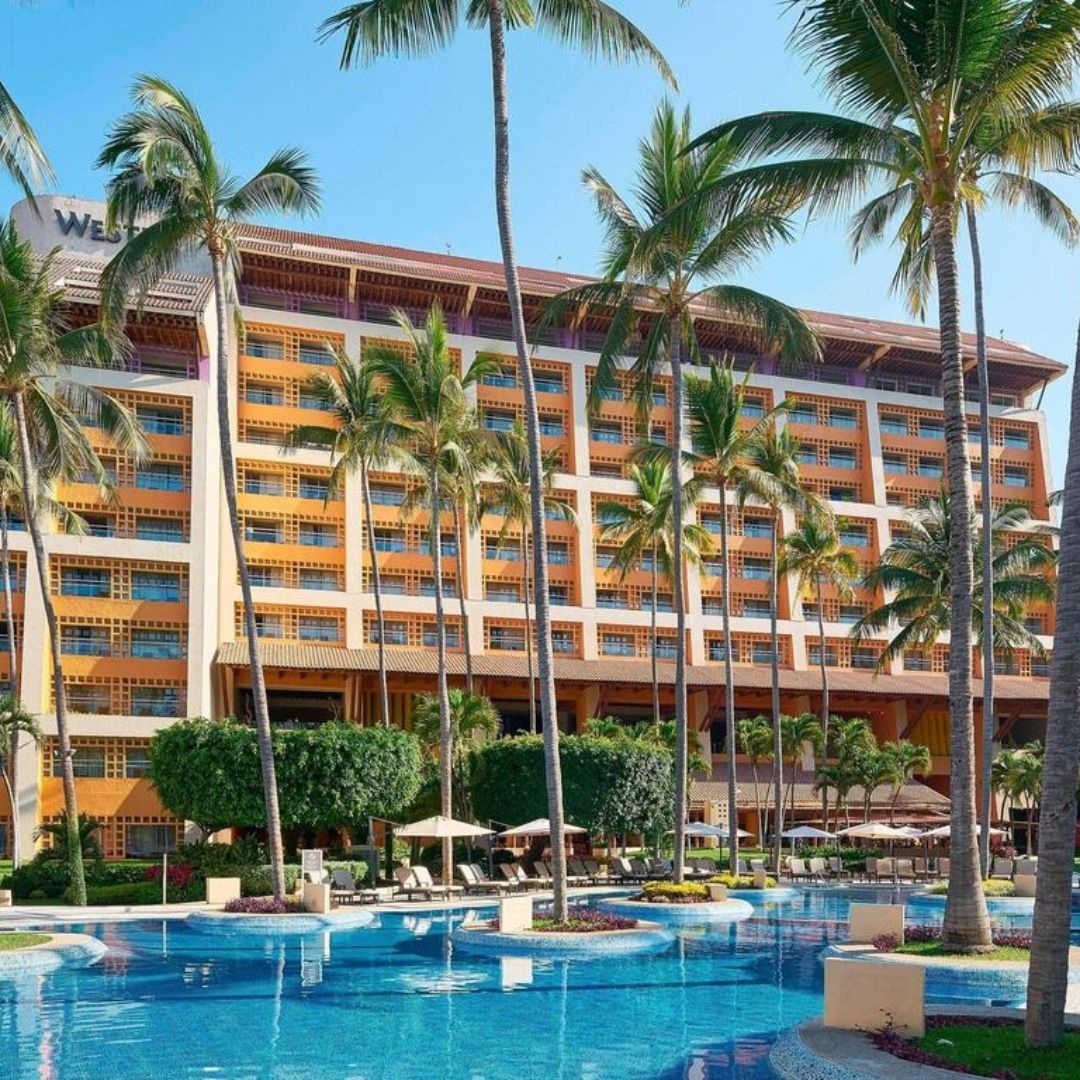A large hotel with a swimming pool in front of it