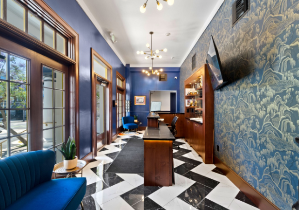 Stylish hallway with blue walls, zigzag black-and-white floor, wood paneling, and windows along the left side