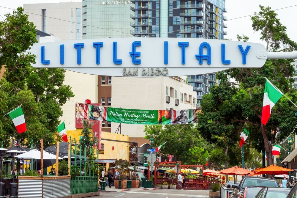 Little Italy entrance sign over a lively street with Italian flags and outdoor seating